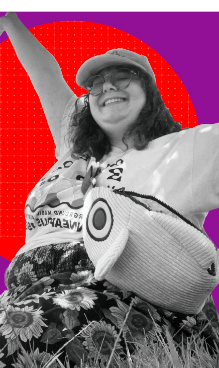 Ly's headshot: a white intersex person with curly hair smiling a big smile, reaching arms up toward the sun. Ly wears a fun fish-shaped fanny pack, a baseball hat, and pants with a bright sunflower pattern.